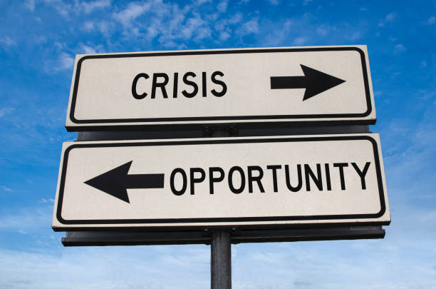 Crisis vs opportunity. White two street signs with arrow on metal pole with words. Directional road. Crossroads Road Sign, Two Arrow on blue sky background. Two way road sign with text. stock photo