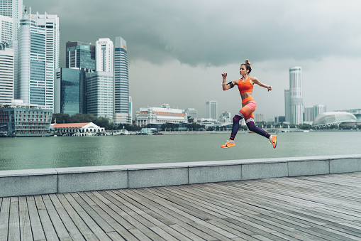 Female athlete running outdoors, with Singapore cityscape in the background