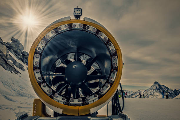snow cannon in front of a ski track in a mountain area