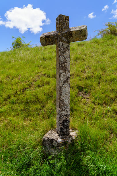istock Stone cross on the green grass field. 1292216542