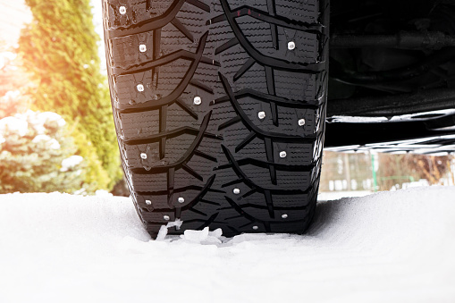 Car tire in the snow close up. Car tracks on the snow. Traces of the car in the snow. Winter tires. Tyres covered with snow at winter road. Winter road safety concept