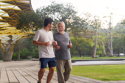 Happy father and son exercising together outdoors in public training fitness park.