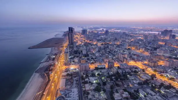 Cityscape of Ajman from rooftop from night to day transition timelapse. Ajman is the capital of the emirate of Ajman in the United Arab Emirates. 4K