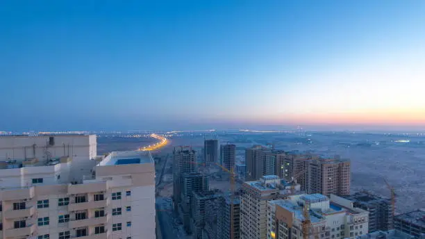 Photo of Cityscape of Ajman from rooftop night to day timelapse. Ajman is the capital of the emirate of Ajman in the United Arab Emirates