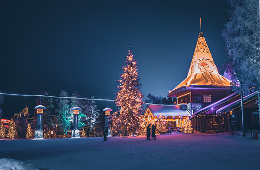 Local people and tourists visiting Santa Claus Village (Joulupukki) amusement park, Arctic Circle, Santa's Office and House of Snowmobiles at night in Rovaniemi in the Lapland region of Finland. It was opened in 1985