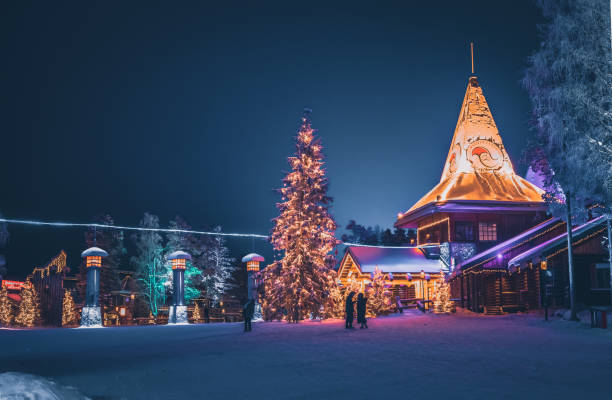 Santa Claus Village and The Arctic Circle in Rovaniemi, Lapland Finland Local people and tourists visiting Santa Claus Village (Joulupukki) amusement park, Arctic Circle, Santa's Office and House of Snowmobiles at night in Rovaniemi in the Lapland region of Finland. It was opened in 1985 finnish lapland stock pictures, royalty-free photos & images