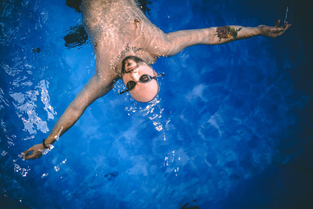 istock Man swimming on back in swimming pool indoors 1292221989