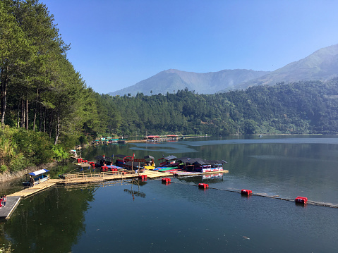 Menjer Lake and Dam in Wonosobo at day, with boats and Dieng hills in the background, Central Java, Indonesia