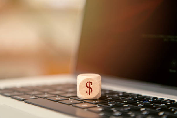 Dollar sign word written on wooden cube on a laptop computer keyboard.
