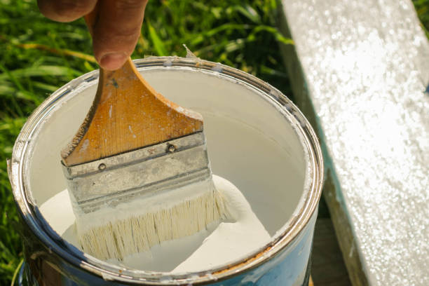 istock Man paints a wooden surface with paint. Brush with can paint 1292229516