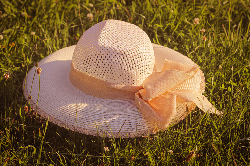 Straw hat on the green grass background. Summer concept. Outdoor recreation. Digital Detox. Unplugging, mindfulness.