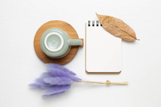 istock Empty notebook and mug cup with purple hares tail grass on white background. top view, copy space. Work and study place 1292229617