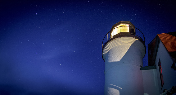 Panoramic lighthouse beacon shining into the night sky at the Point Betsie Lighthouse on the coast of Lake Michigan.
