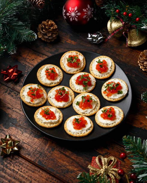 caviar de salmón y galletas saladas de queso suave con decoración, regalos, rama de árbol verde en mesa rústica de madera. - appetizer salmon smoked salmon cracker fotografías e imágenes de stock