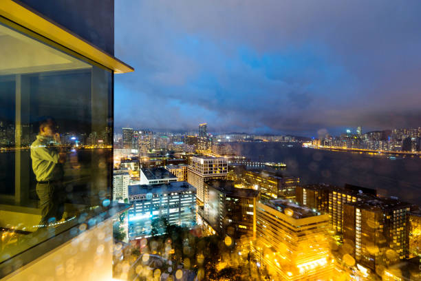 Businessman standing by the window with hand on chin at night.