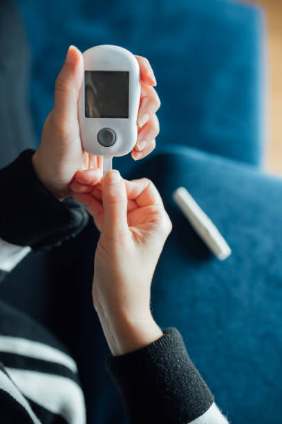 diabetes verificando o nível de açúcar no sangue. mulher usando lancelet e glucometer em casa - diabetes blood illness chronic - fotografias e filmes do acervo