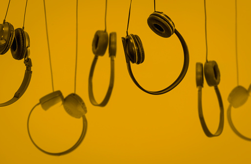 Headphones hanging on yellow background.