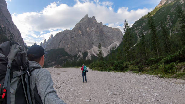 istock Oberbachernspitze - A couple with big backpacks taking a selfie while hiking at the bottom of a valley in Italian Dolomites. 1292243136