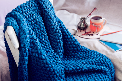 blue knitted plaid on a chair and coffee with cezve in the background
