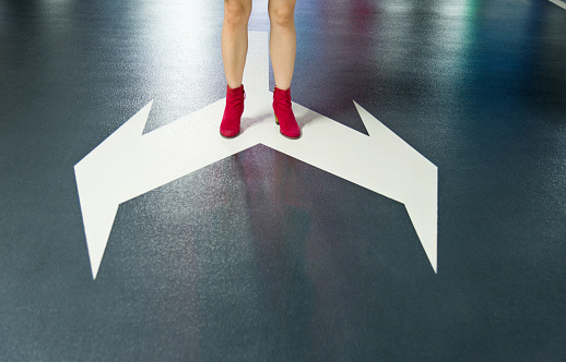 Woman standing on white direction arrow.