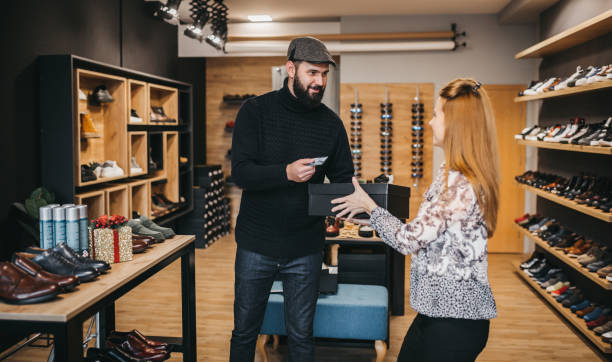 mann bezahlt mit karte in schuhgeschäft - shoe store sales clerk customer stock-fotos und bilder