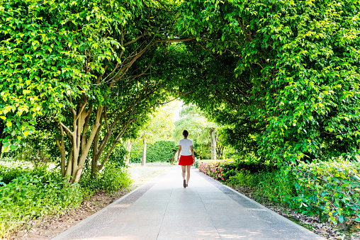 Woman walking through green natural tunnel.