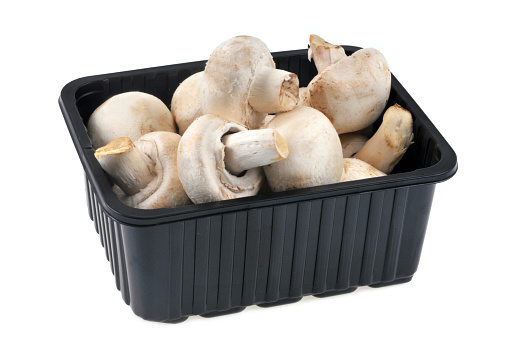 Tray of raw mushrooms in close-up on a white background