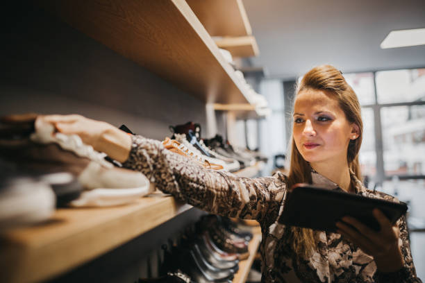 woman in a shoe store using tablet - shoe women fashion shoe store imagens e fotografias de stock