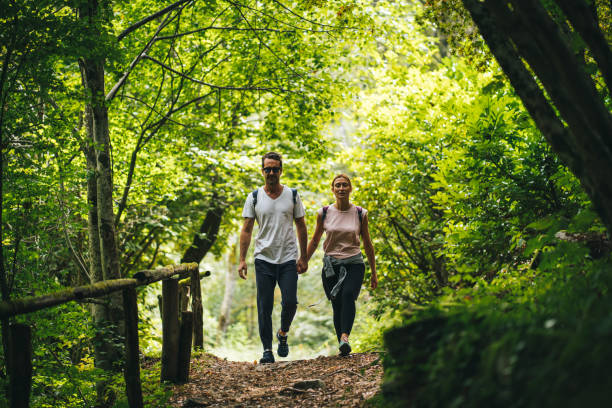 Couple hike along forested trail in the morning stock photo