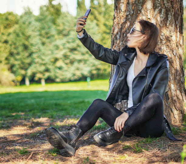 istock Young beautiful woman taking selfie under the tree 1292253934
