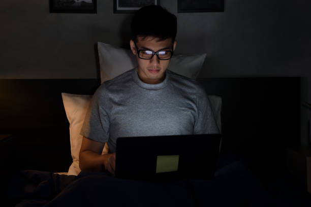 istock Young Asian man using a laptop in his bed at night 1292258615
