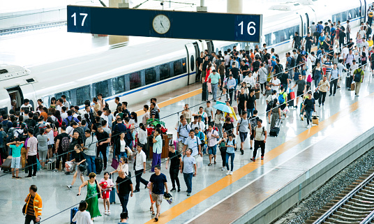 Crowd of passengers waiting on station platform.