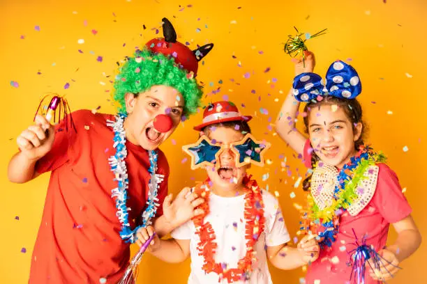 Three kids celebrating Carnival or New Years Eve at home