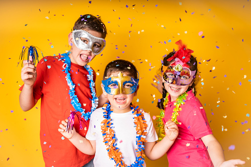 Three kids celebrating Carnival or New Years Eve at home