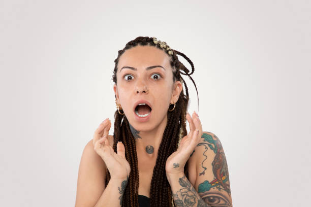 шокированная женщина с плетеные волосы и татуировки на белом фоне - studio shot mouth open horizontal head and shoulders стоковые фото и изображения