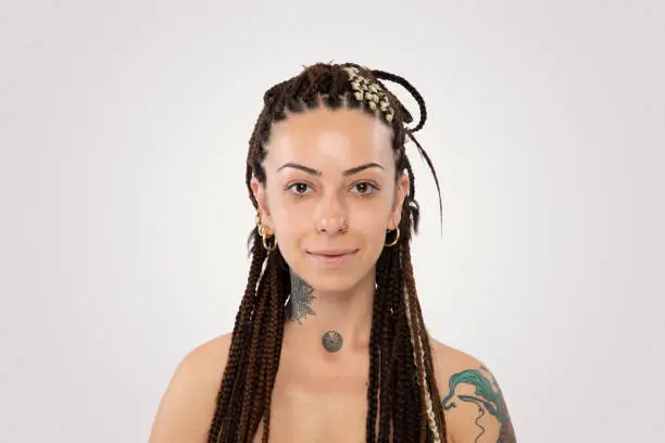 Stylish woman with braided hair and tattoo smiling over white background.Woman with braided hair and tattoo over white background