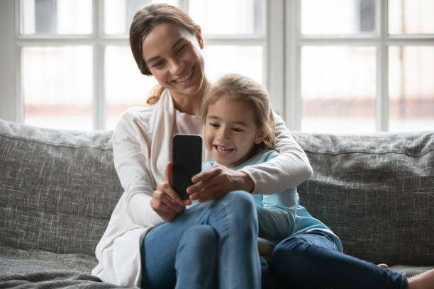istock Smiling mom and small daughter use smartphone at home 1292260714