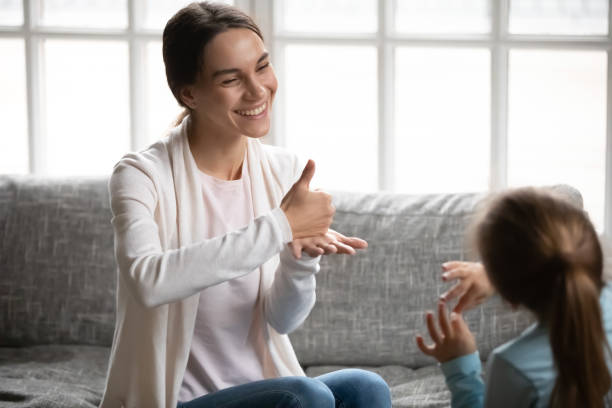 istock Smiling mom use sign language talking with small daughter 1292260733