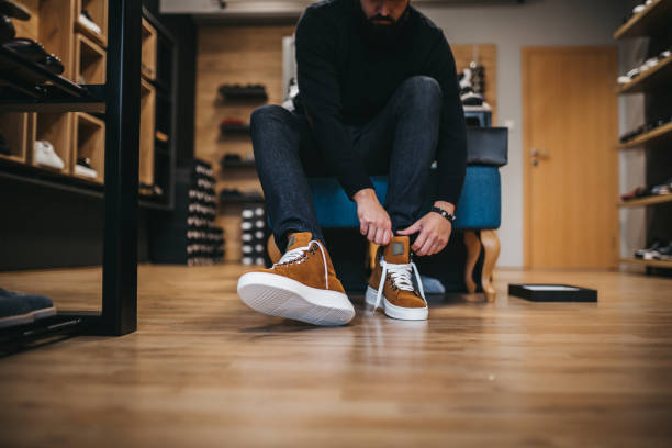 junger mann einkaufsschuhe - schuhgeschäft stock-fotos und bilder