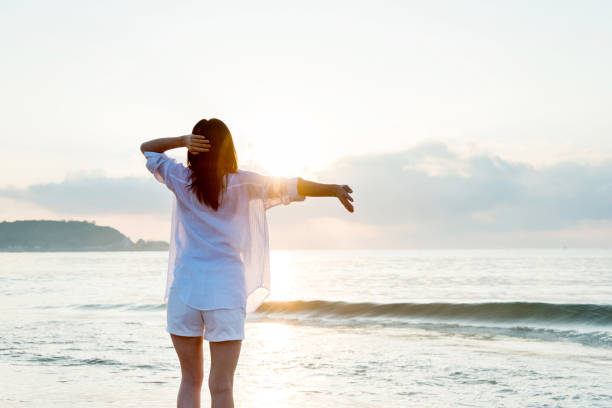 istock Young woman standing on beach with arms outstretched 1292261140