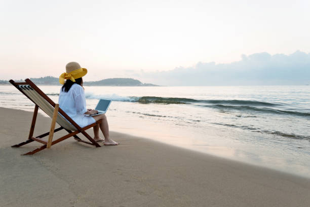 istock Woman using laptop at the beach 1292261989