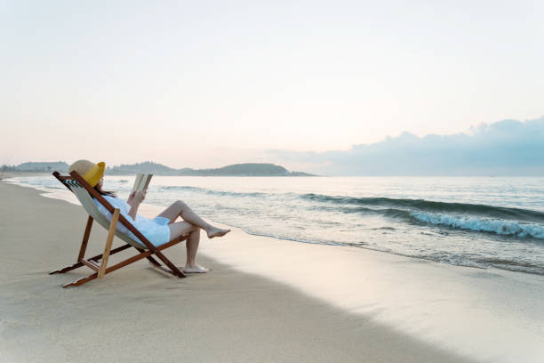 istock Woman reading book at the beach 1292262053