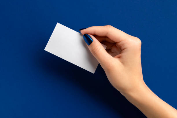 istock Womans hand holding paper card on blue background 1292262385