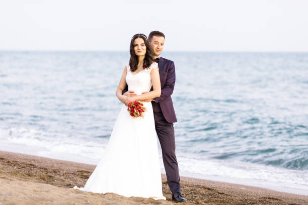 Beautiful newlywed young couple walking on beach