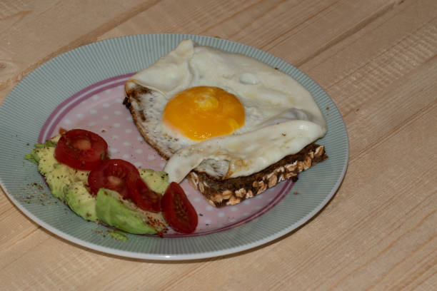 istock Fried egg on wholemeal bread with sliced avocado and tomato arranged on a plate. 1292266364