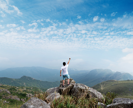 Man on the top of mountain with arms raised.