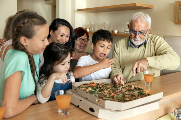 istock Multi-Generation Family Around Kitchen Island is Eating Tasty Pizza. 1292268745