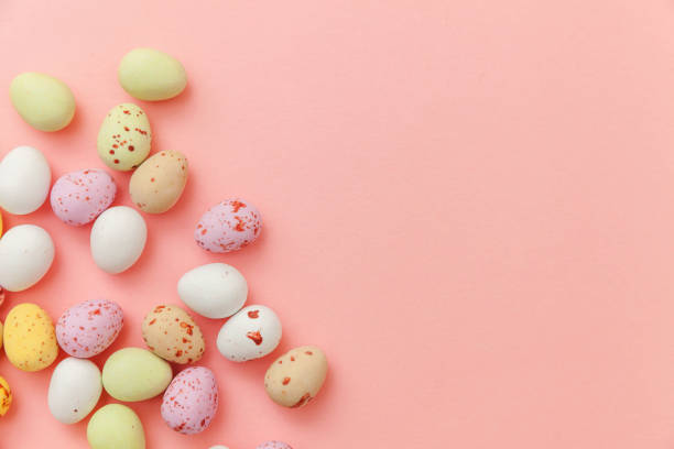 istock Happy Easter concept. Preparation for holiday. Easter candy chocolate eggs and jellybean sweets isolated on trendy pastel pink background. Simple minimalism flat lay top view copy space 1292268816
