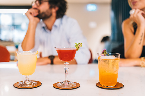 Friends enjoy cocktails in brightly lit bar