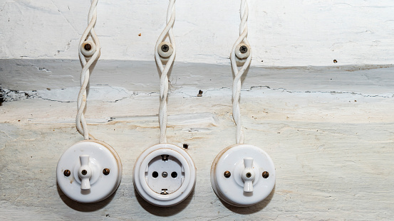 Retro socket and two switchs. A vintage outlet and electrical wiring on white wooden wall background.
